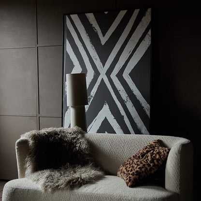 Black and white cross line pattern in a thin black frame behind a cream sofa