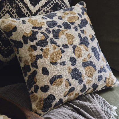 Close up of a camouflage style animal print cushion with a cream background and earthy colours. 