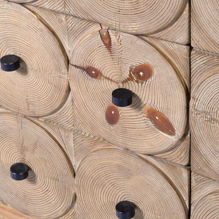 A close up of the Myton Sidebaord, showing circular wooden details on the drawers with a black handle. Reclaimed pine wooden sideboard with a textured natural finish, decorative circular detailing and statement black handles. By Abigail Ahern, 