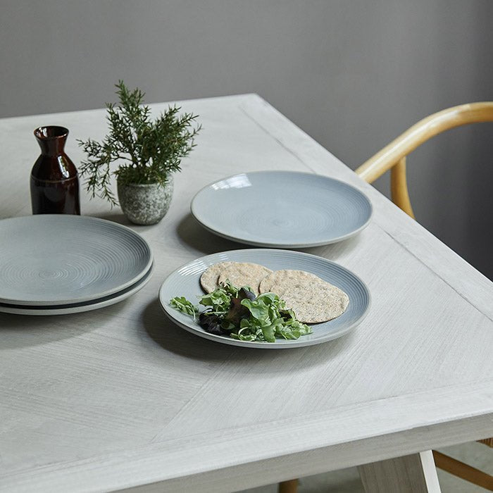 Bronson Parquet Dining Table, a rectangular herringbone wooden dining table styled with a set of light grey plates.
