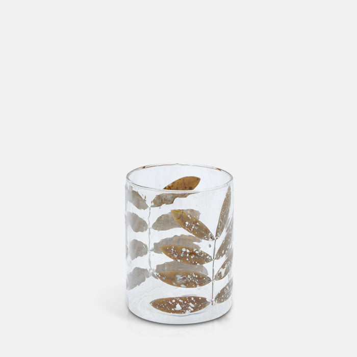 Clear glass candle holder decorated with dried leaves on either side.