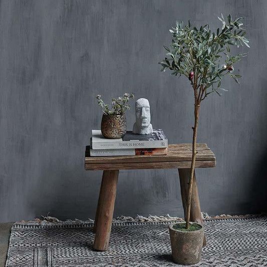 An artificial olive tree sat in front of a wooden stool