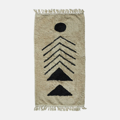 Cream tufted cotton rug with tasseled ends and black geometric motif.