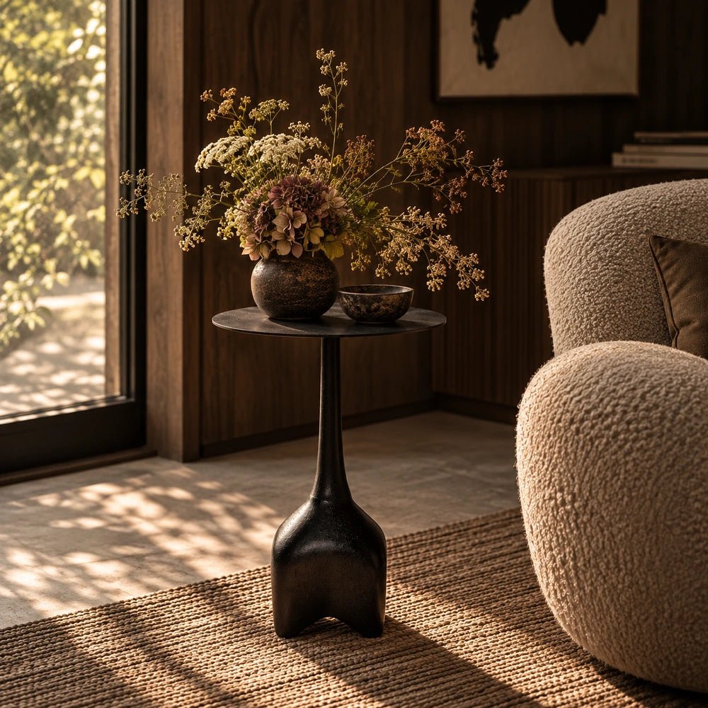 Oren Side Table in black with a sculptural rounded metal form, styled beside neutral upholstered seating with decorative objects in a contemporary interior.
