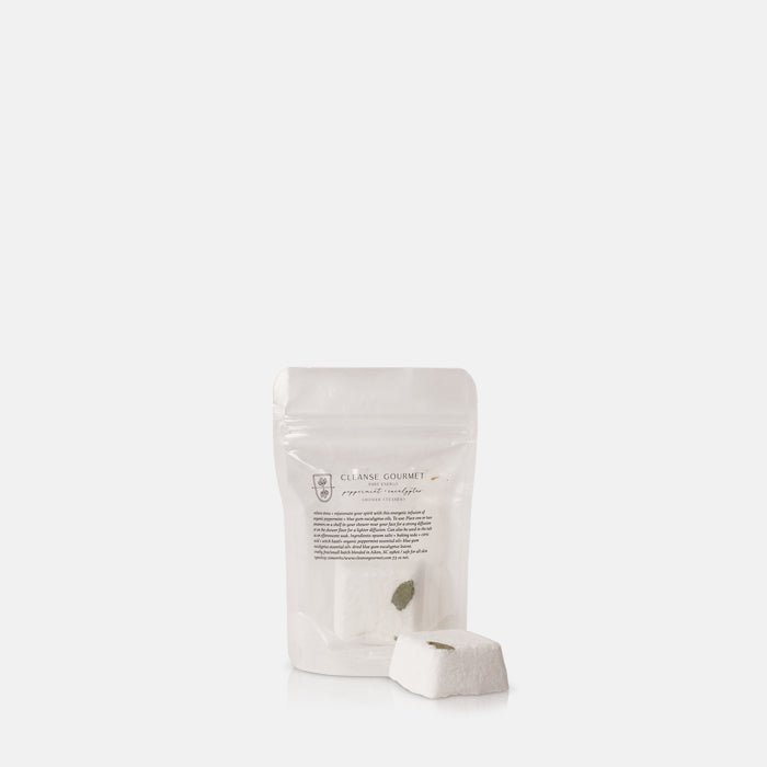 A single white Eucalyptus and Peppermint Shower Steamer, placed in front of its translucent packaging.