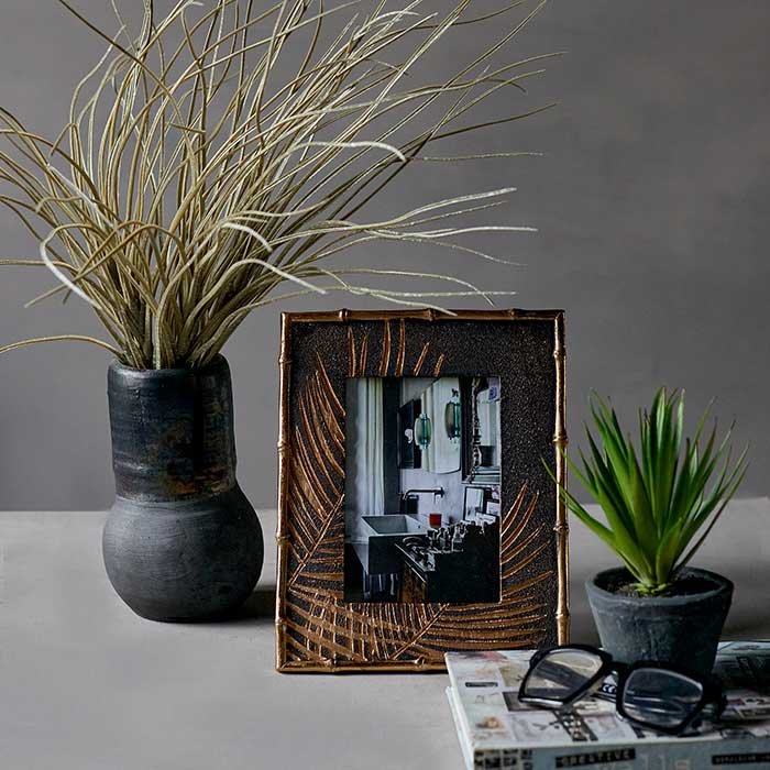 Spiky potted plant next to a photo frame and grey vase