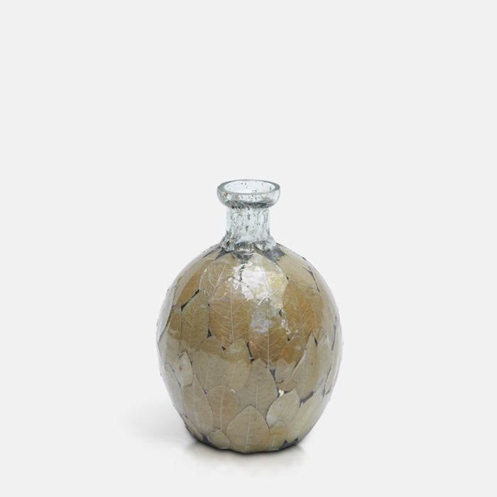 Curved glass bottle vase, with natural dried leaves covering the body.