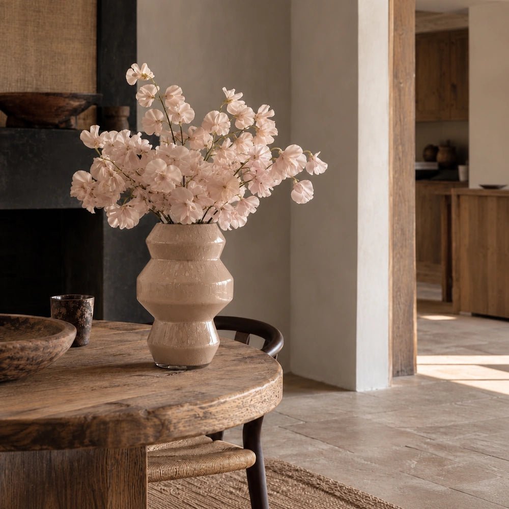 Palermo Glass Vase styled with autumnal branches on a wooden surface, showing its rounded smoky glass silhouette, warm neutral colouring and artisanal finish.