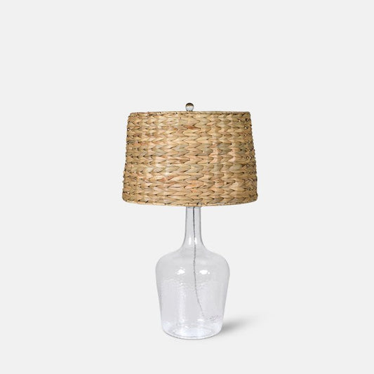 Large table lamp with clear glass base and woven bamboo shade.