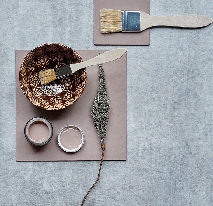Flatlay of a painted swatch styled with a hand painted ceramic bowl, a natural paintbrush and a faux botanical draped across the bowl.