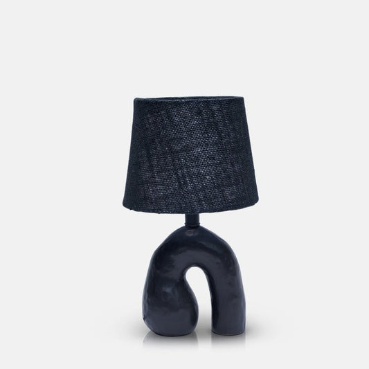 Small black table lamp with sculptural ceramic base in shape of upside down 'U'.