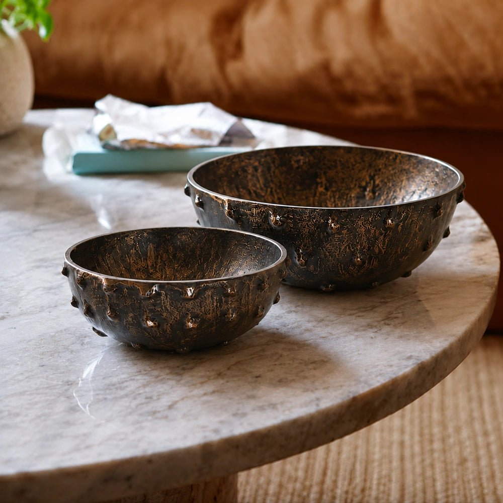 Portrush Metal Bowls set of two styled on a dark wooden console with a sculptural lamp, smoky glass vase and warm neutral interior backdrop.