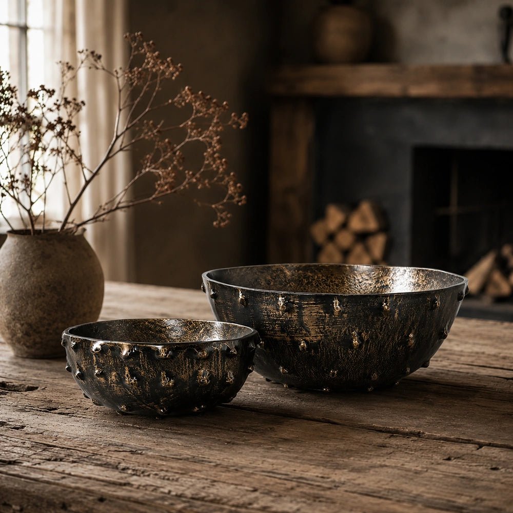 Portrush Metal Bowls set of two styled on a dark wooden console with a black sculptural vase, warm lamp and softly textured neutral wall.
