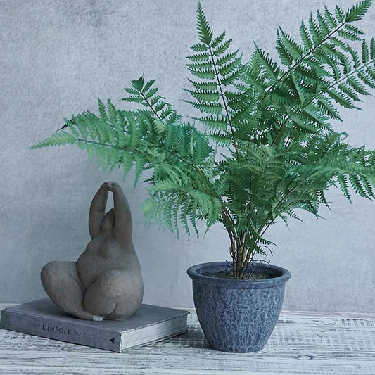 Artificial fern plant, with green foliage and a grey pot.