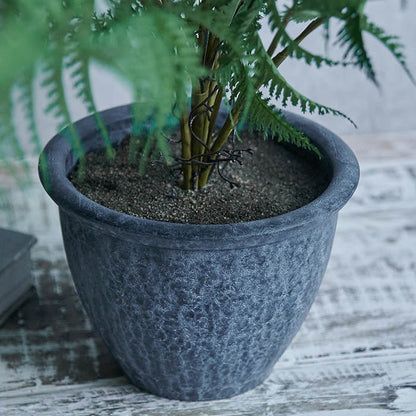 Grey plastic pot holding artificial fern plant.