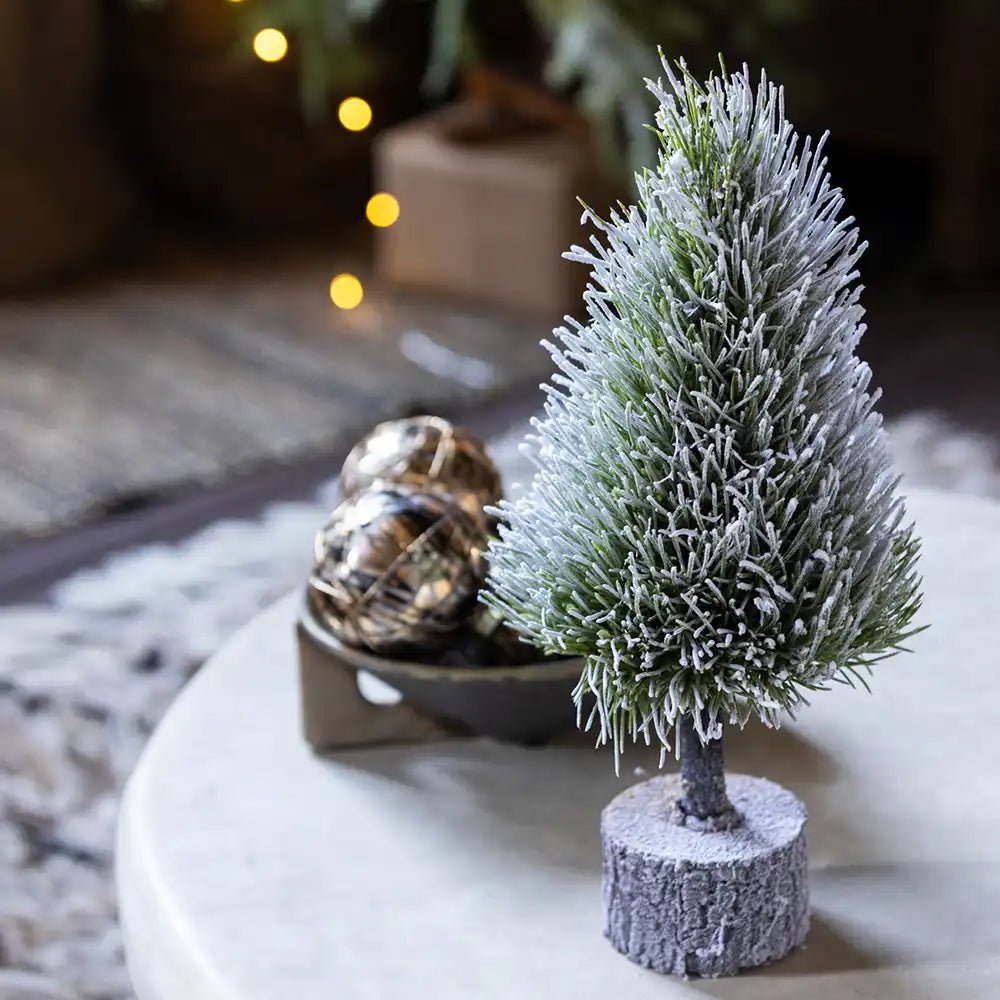 Pre-Lit Mini Christmas Tree with snow-like texture and festive ornaments on a decorative table.
