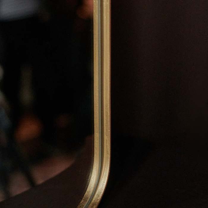 Thin gold frame wrapping around the edge of a rectangular mirror