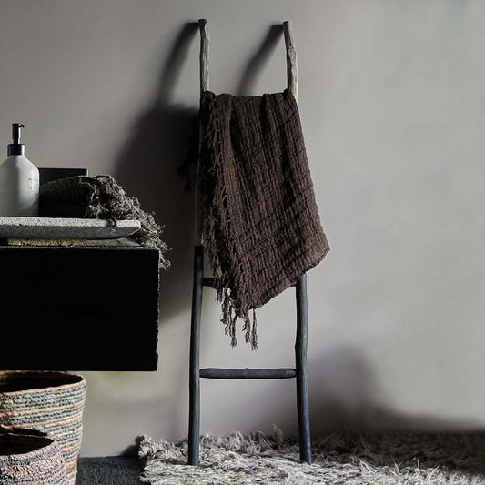 Chocolate throw on a wooden ladder leant up against a warm grey painted wall