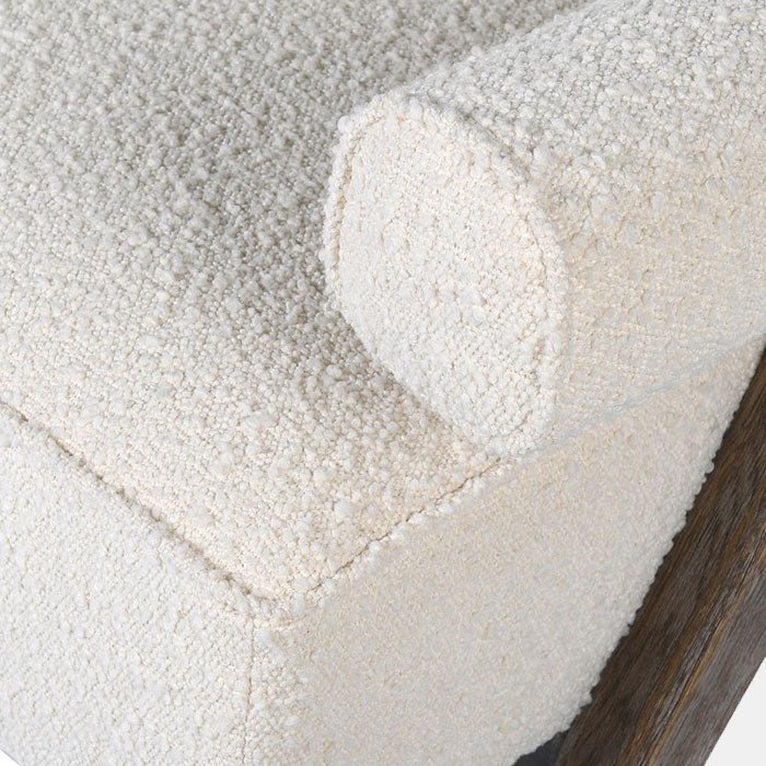 A closeup of the cream boucle upholstery on the padded armrest and seat of the Realta Cream Boucle Armchair.