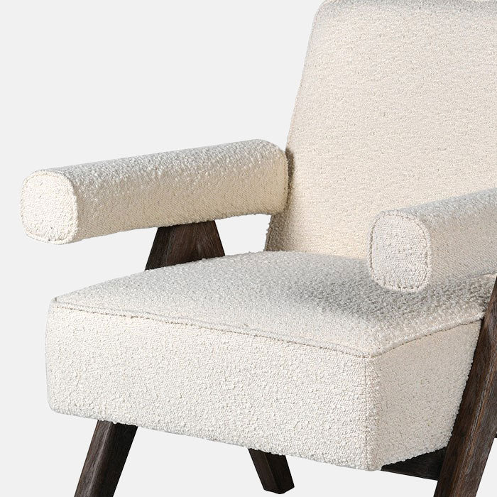 The Realta Cream Boucle Armchair, a dark wooden framed angular chair with a tilted seat and padded armrests in cream boucle.