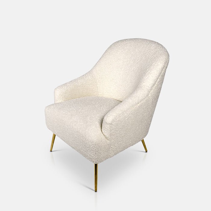 Cream boucle armchair with a high back sat on four golden legs