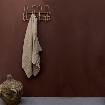 Beige towel hanging on a hook on a rich red-brown painted wall