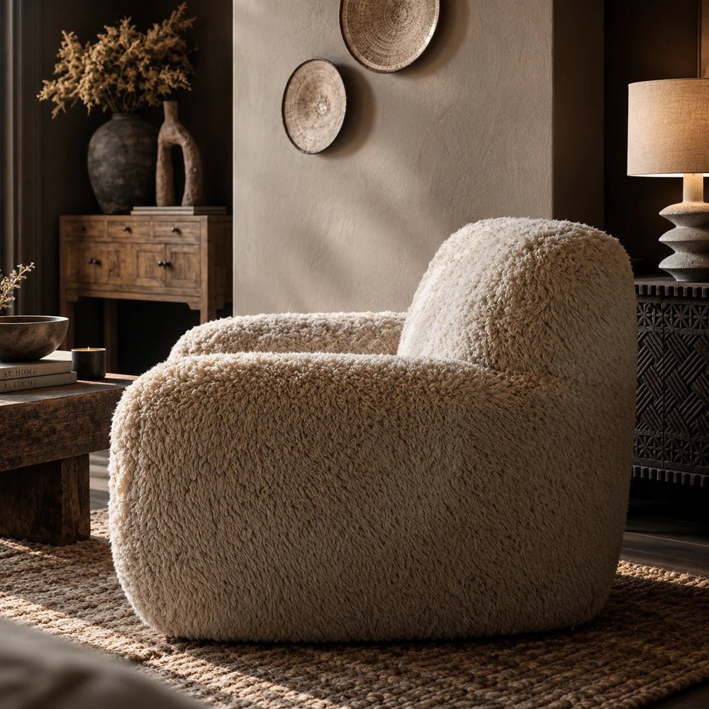 Saskia Cream Faux Fur Armchair with oversized rounded silhouette and shaggy textured upholstery, styled in a warm living room with neutral furniture and ceramics.