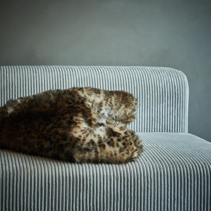 Faux fur leopard print throw folded on a grey sofa