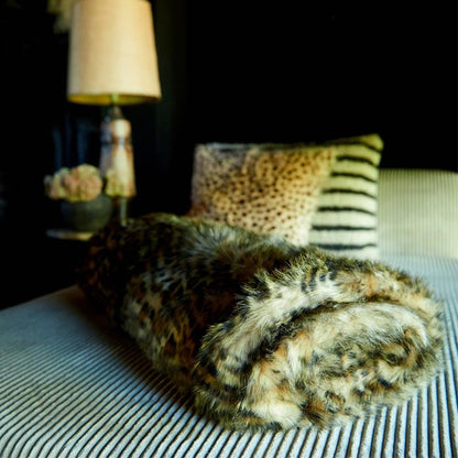 Faux fur leopard print throw rolled on a bed