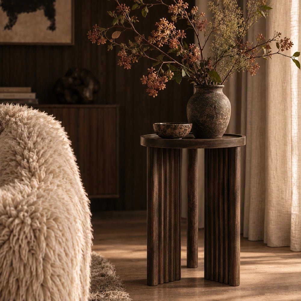 Shoreditch Wooden Side Table with dark rounded top and vertical slatted base, styled beside curtains, decorative ceramics and foliage in a warm living room.