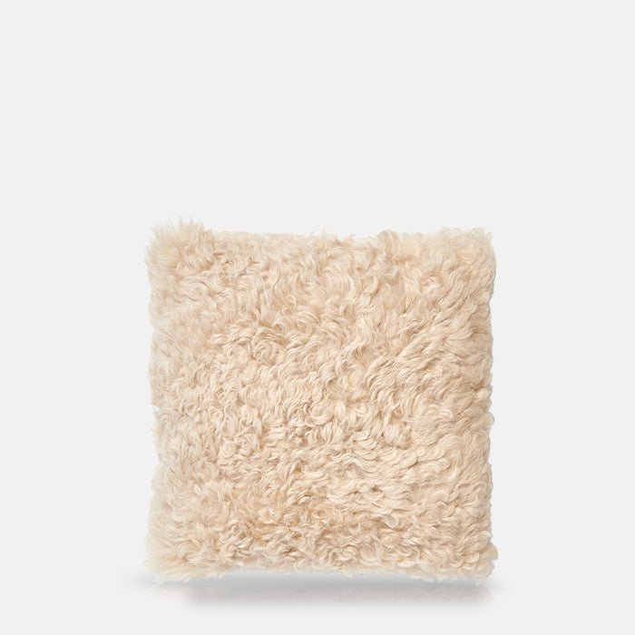 Cutout image on a white background of a square, cream sheepskin cushion with a shaggy texture