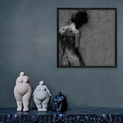 Black framed print of a female figure hung above 3 female sculptures