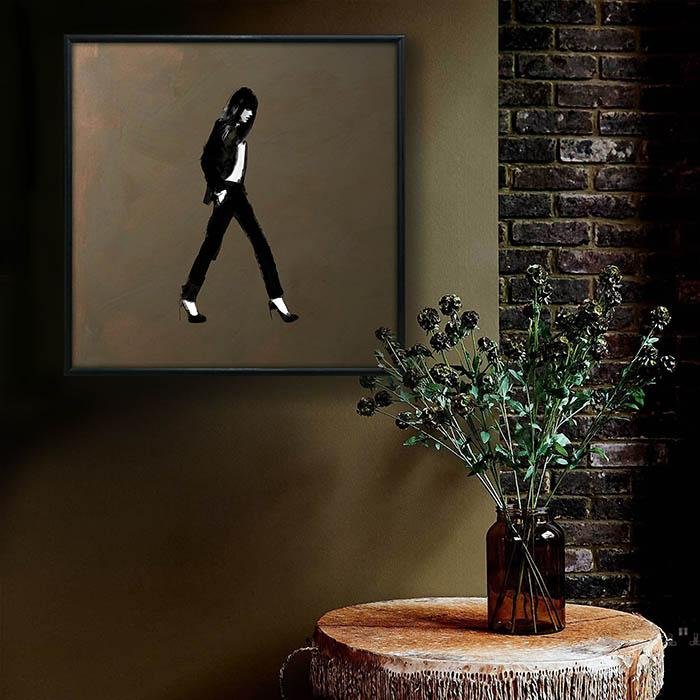 Square framed print of a monochrome walking figure hung on a wall