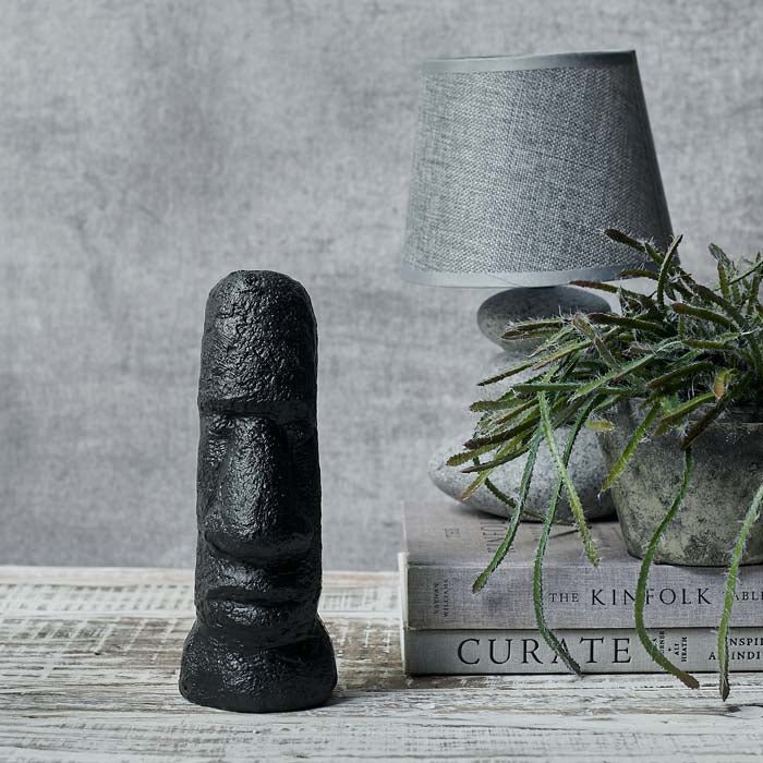 Long face and shoulders sculpture in black sat next to a pile of books