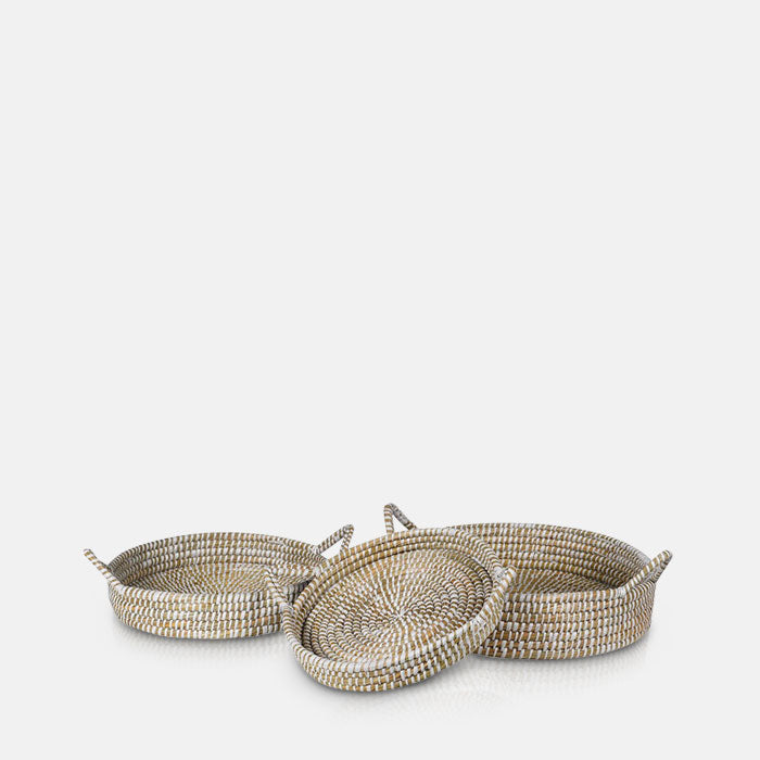 Three different sized seagrass trays with handles laying next to eachother