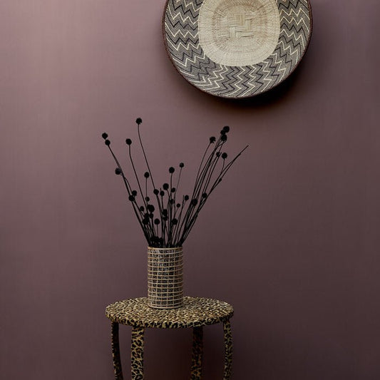 Leopard print table with black dried flowers on top in front of a rich pink painted wall