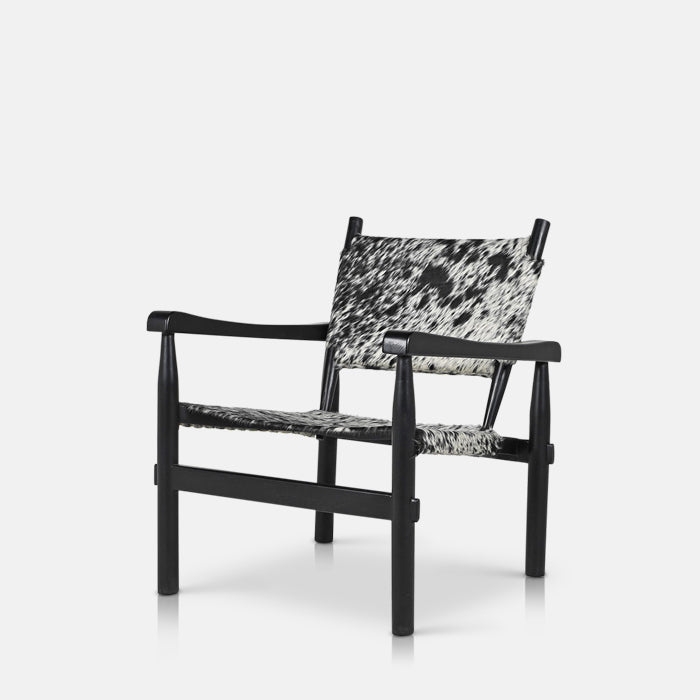 A cutout of the Tilbury Hide Chair, a mid-century style accent chair featuring cowhide print and a sleek black wooden frame.