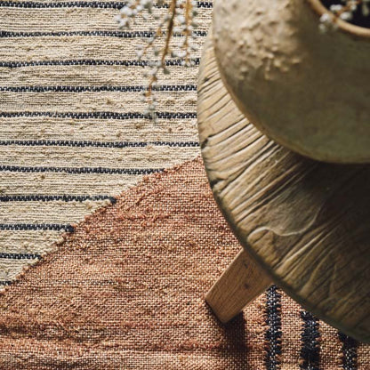 Detail of the texture of a woven jute rug in orange and cream colours with a striped pattern