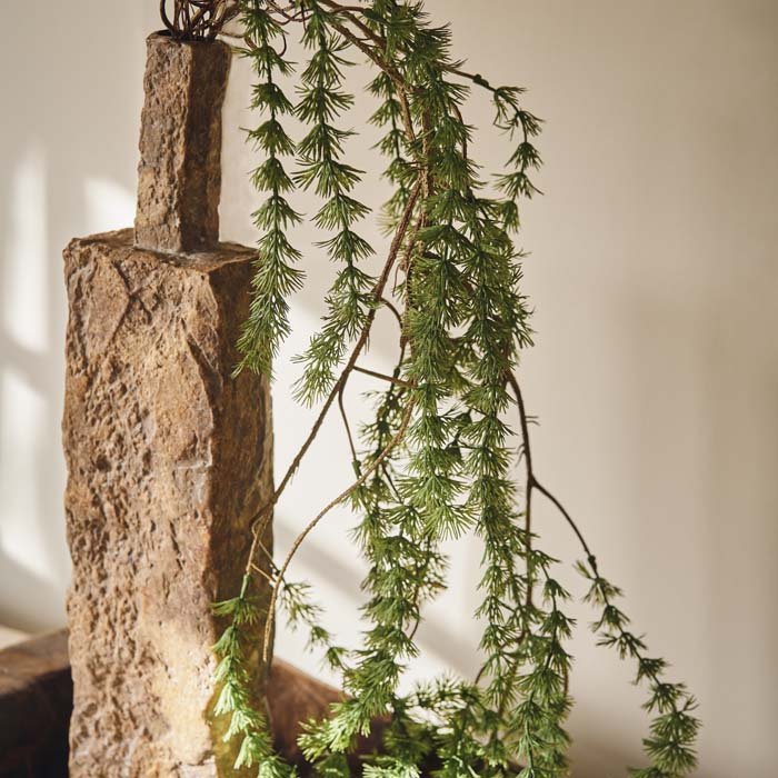 A very textured brown vase with some trailing faux botanicals