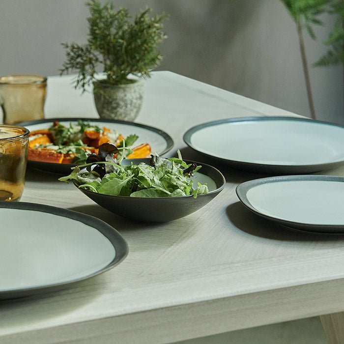 Truman Stoneware Dinner Set - 12 Piece, a set of white and black organic shaped tableware styled with food on a wooden table.