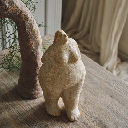 A tall standing female sculpture with her arms behind her back. Cream coloured sculpture, neutral colour home accessory for a unique home.