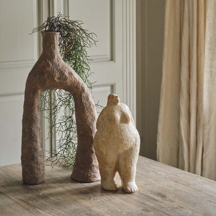A large standing female sculpture. Cream coloured female figurine styled next to an unusual shaped vase. Female figurine to add an arty look to your home. 