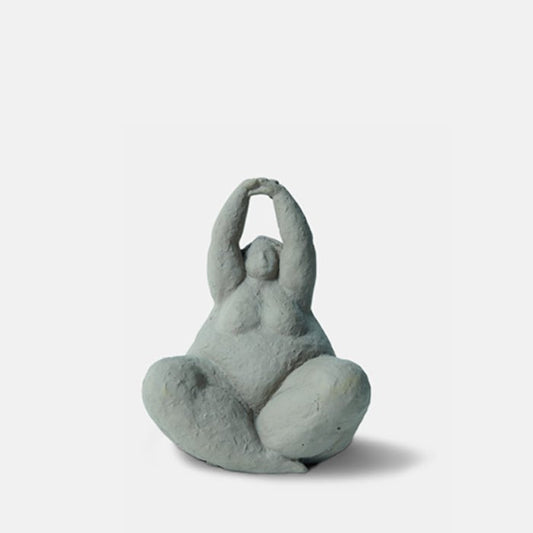 Crossed leg grey female sculpture with arms raised above its head