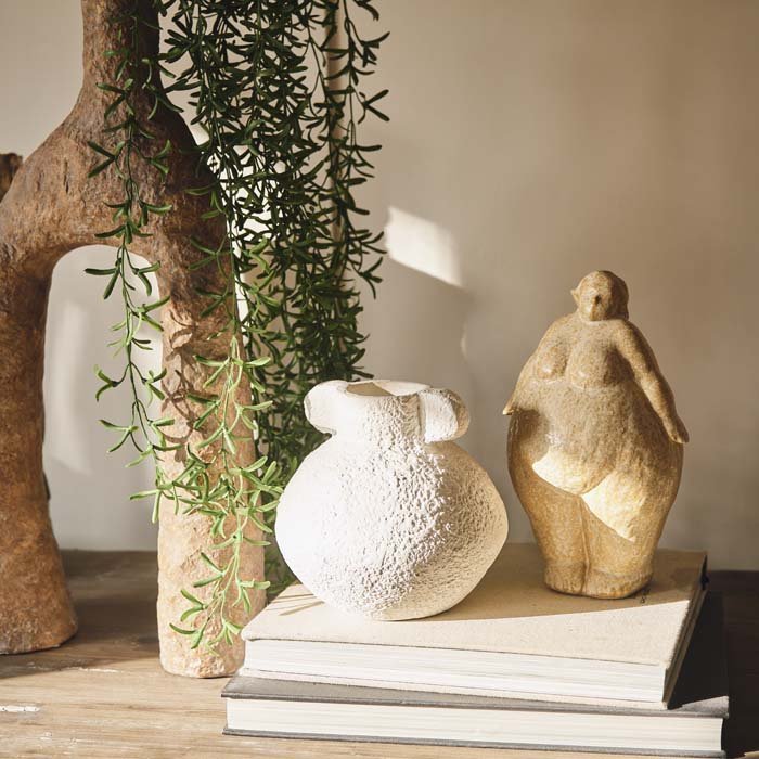 Ceramic sculpture of a standing female styled on a stack of design books and a bud vase. Add some unique style to your home decor with sculpture.