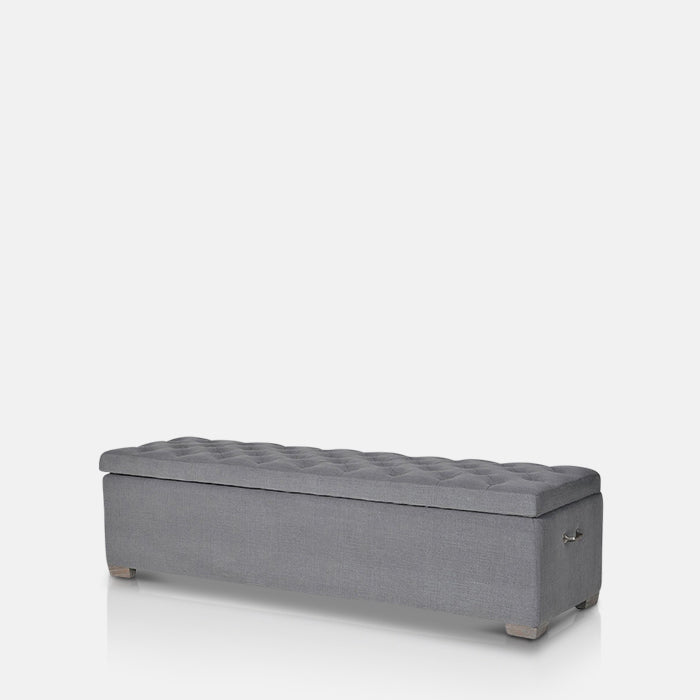 A cutout of the Vida Bedding Box, a rectangular storage trunk upholstered in a soft grey with a quilted style top panel.