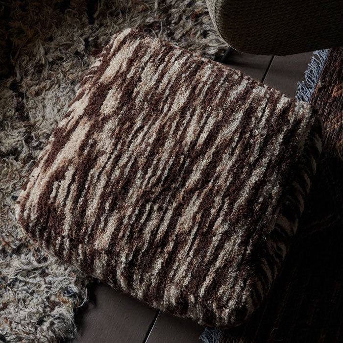 Square floor pouffe in tufted brown and cream wool.