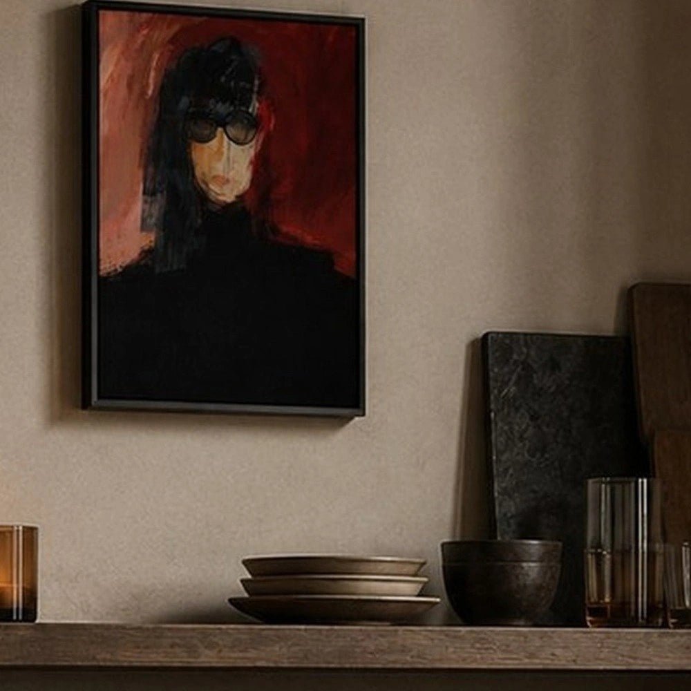 Ada portrait artwork displayed above a dark console, featuring a woman with sunglasses against a vivid red background beside sculptural neutral decorative objects.
