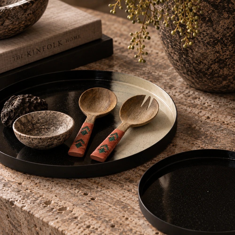 Alba Wooden Salad Servers with carved wooden spoon and fork, wrapped coral and green handles, styled on a black tray with decorative bowls and foliage.