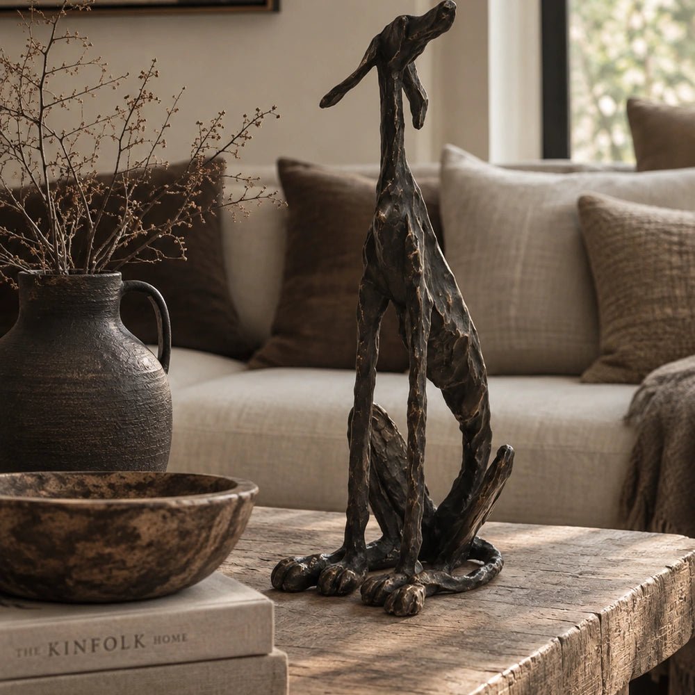 Arnie Sculpture displayed on a rustic coffee table in a neutral living room, beside textured vessels, branches and layered upholstered seating.