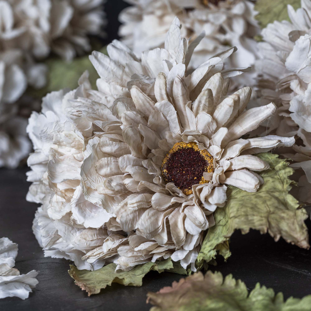 Close-up of a white artificial flower with a brown center on a dark surface.